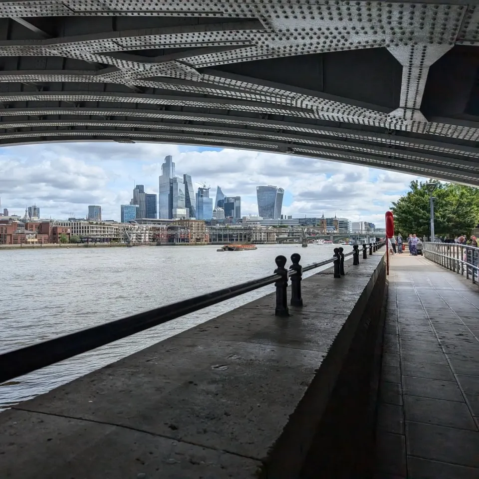 The City of London skyline framed by the underside of a bridge on the South Bank