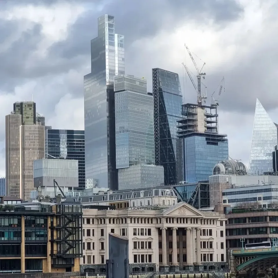 City of London towers under a cloudy sky, with a classical building in front