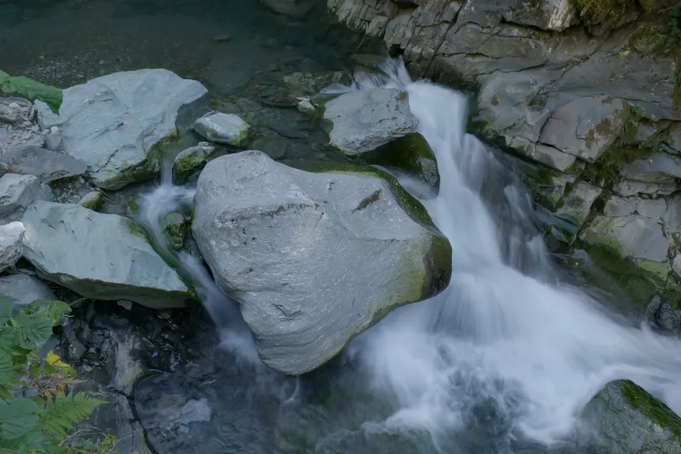 A mountain stream rushing around a large grey boulder