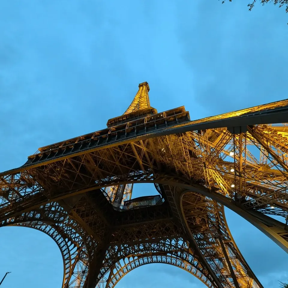 Looking up through the iron lattice of the Eiffel Tower